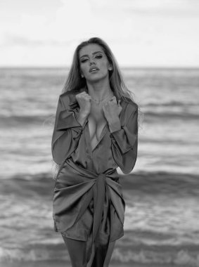 Yaz modası trendi. Güzel, romantik bir kadın okyanus mavisi arka planda güneşleniyor. Yaz tatili. Kumsalda dinlenen kadınlar, lüks yaz tatili, açık deniz geçmişi.