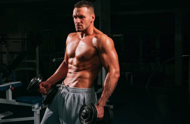 Çıplak erkek gövdesi. Dambıllar. Spor salonundaki sporcu. Spor egzersizleri. Erkek 6 paket.