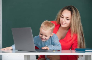 Dizüstü bilgisayar kullanan okul çocuğu. İlkokul öğretmeni ve öğrenci sınıfta. Anne ve oğlu birlikte bilgisayar laptopu kullanıyorlar.