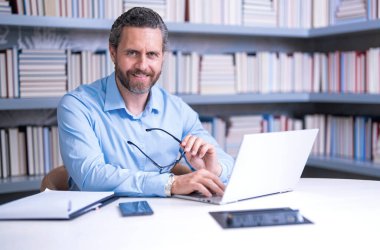 Kütüphane sınıfındaki öğretmenin portresi. Üniversite kütüphanesinde yakışıklı bir öğretmen. Öğretmenler Günü. Öğretmen ders veriyor. Kütüphanede öğretmen. Üniversite kütüphanesinde ders veriyorum.