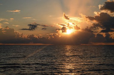 Tropikal sahilde gün doğumu denizi. Güzel bir sahil manzarası. Denizde güzel bir gün batımı. Gökyüzünde gün batımı ve renkli bulutlar. Denizin üzerindeki bulutlar, güneşin doğuşu. Okyanus dalgası