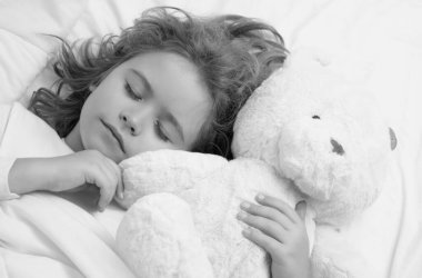 Günlük uyku. Tatlı çocuk yatakta oyuncak bir ayıyla uyuyor. Uyuyan çocuk