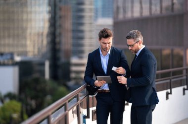 Finansal büyüme, çevrimiçi iş. Takım elbiseli iki iş adamı dışarıda kredi kartı ve laptop tableti tutuyor. Hesabı öde. Şehirde kredi kartı olan bir adam. İş anlaşması. E-para. Başarı işi