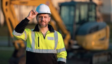 İnşaat alanında çalışan bir inşaatçı. Kazıcı yeni bir ev inşa etmeye hazır. İnşaatçılar kazı kamyonu kazılarında inşaat üniforması giyerler. İnşaat geçmişi olan inşaatçılar.