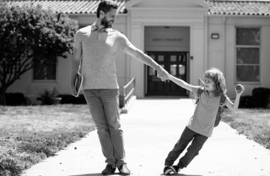 Baba ve oğul okula, eğitime ve öğrenmeye giderler. Sırt çantalı ilkokul öğrencisinin ebeveyni ve öğrencisi.