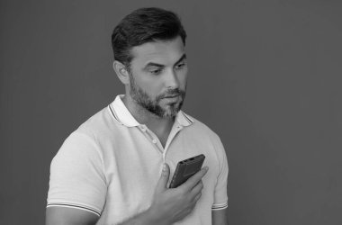 Memnun iş adamı telefonda konuşuyor, tanıtım amaçlı mobil uygulama. Stüdyonun arka planında izole edilmiş akıllı telefon kullanan sıradan giyinmiş bir iş adamı. Cep telefonu kullanan, sosyal medyayı karıştıran neşeli adamın portresi