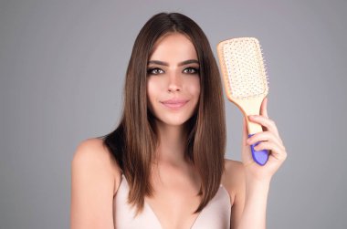 Beautiful woman with brush combing hair. Beauty girl with straight hair isolated on studio background. Woman hold hairbrush near face. Healthy hair. Hairstyle and hair care concept. Shiny hairs