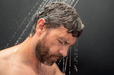 Adam banyoda duş alıyor. Adam sabah duşu alıyor. Duş başlığından su altında saç yıkamak. Yakından duş alan adam. Vücut bakımı hijyeni. Duş konsepti. Suyun altındaki adam duşta düşer.
