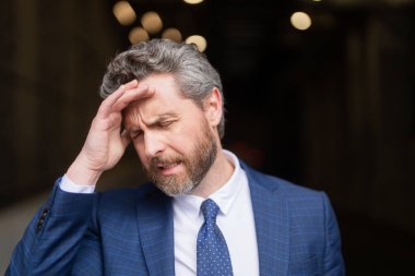 Üzgün iş adamının migreni tuttu. Güçlü baş ağrısı olan bir adam. Stresli, baş ağrısından yorgun iş adamı. Baş ağrısı, yorgunluk ve stres, migren. Baş ağrısı konsepti