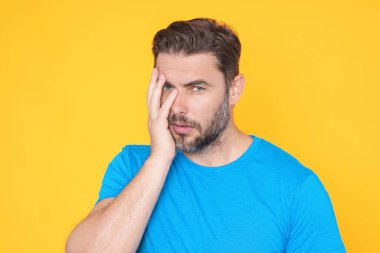 Sarı arka planda eli çenesinde duran yakışıklı bir adam soru soruyor. Düşünceli bir ifade. Düşünceli bir yüz. Şüpheli bir kavram. Kafa karıştırıcı bir fikir hakkında düşünceli bir soru.