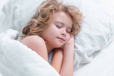 Küçük çocuk uyuyor. Çocuk kestiriyor. Yatakta uyuyan çocuk, yatak odasında rahat bir yatak. Sağlıklı uyku konsepti. Yumuşak yastık, rahat, rahat yatak