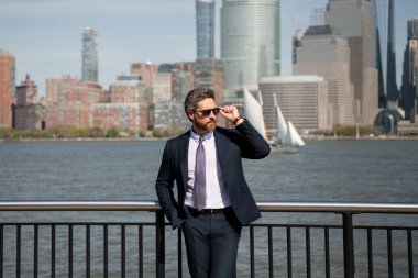 New York 'ta başarılı bir iş adamı olarak duruyor. İş dünyası Amerikan başarısı. Amerikan iş rüyası. Manhattan yakınlarında takım elbiseli Amerikalı işadamları. ABD 'de başarılı bir iş