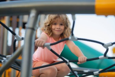 Portrait of child doing rock climbing with background playground