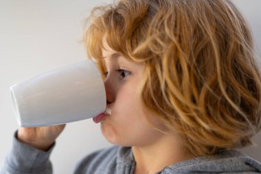 Kid holding a glass of fresh milk. Child with milk moustache drinking milk. Healthy breakfast for children. Healthy eating concept for kids. Little kid boy hold cup of milk