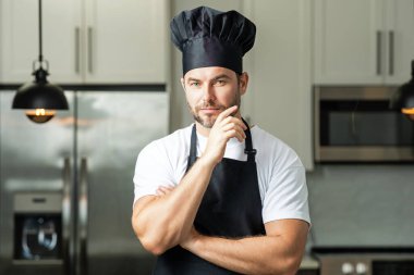 Yemek için fikir. Aşçı aşçı adam. Milenyum aşçı üniformalı erkek şef. Aşçı mutfakta yemek pişiriyor. Aşçı şapkalı ve önlüklü