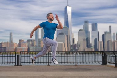 Sokakta spor yapan olgun bir adam. Koşucular açık havada koşuyor. Kentsel alanda sporcu eğitimi, sağlıklı yaşam tarzı spor konsepti. New York 'taki halk parkında spor kıyafetleri içinde koşan bir adam.