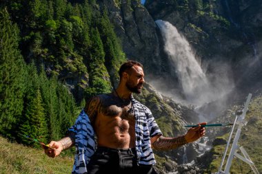 Yaratıcı sanatçı doğa manzarası çiziyor. Dışarıda seksi bir adam çiziyor. Erkek sanatçı kırsalda resim çizer. Erkek sanatçı tuvale bir resim çizer. Çadır fırçalı adam