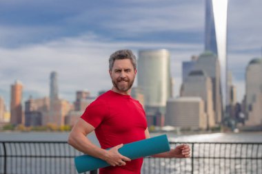 Spor salonundaki adam Manhattan yakınlarında egzersiz yapıyor. Sağlıklı fitness yaşam tarzı. Aktif kıdemli adam dışarıda fitness egzersizi yapıyor. Emeklilikten sonra spor. Olgun emekli sporcu esneme egzersizleri yapıyor.