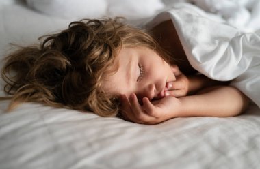 Sevimli küçük çocuklar uyuyorlar. Sağlıklı ve huzurlu bir uyku çekiyorlar. Altı yaşında bir çocuk yatakta uyuyor.