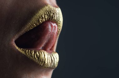 Seksi dil yalayan dudaklar. Altın parıltılı ruj. Seksi dudak için parlak bir tarz. Şehvetli kadın dudakları. Şatafatlı altın ağız. Parlak altın dudaklar. Altın boyalı altın dudaklar veya metalik ruj