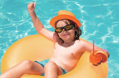 Kid floating in pool. Child relaxing in pool, drink summer cocktail. Summer holidays and vacation with kids. Happy little boy playing in swimming pool outdoor on hot summer day