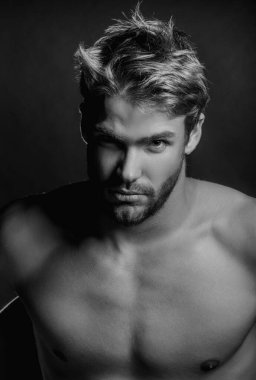 Seksi erkek stüdyo portresi. Çekici erkek yüzü gölgede, kameraya bakıyor. Seksi erkek stüdyo portresi. Siyah stüdyo resmindeki yakışıklı adam. Genç, ciddi erkek suratı. Siyahların üstünde poz veren yüksek moda adamı.