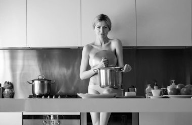 Sabahları mutfakta çıplak seksi bir kadın ve sağlıklı yemekler pişiriyor. Şehvetli ev hanımı.