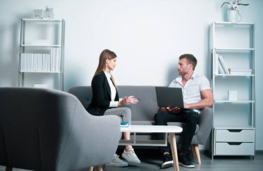 İş arkadaşları konuşuyor. Ofiste dizüstü bilgisayarla çalışan iki genç iş adamı.