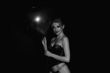 Seksi iç çamaşırları. Siyah iç çamaşırlı güzel bir kadın elinde kırmızı kalp şeklinde balonlar, sevgililer günü. Şehvetli iç çamaşırlı seksi bir kadınla romantik bir randevu. Sevgililer Günü 'nü kutlayan kadın