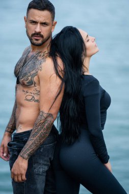 Loving people, lovely couple in love. Sexy girl and fit muscular boyfriend with naked bare torso kissing outdoor. Tattooed Hispanic man posing with sexy woman outdoor