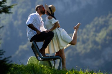 Dağ manzarasında birbirine aşık romantik çift. Mutlu çift gezgini Alplerin tadını çıkarıyor. İki Sevimli Turist yaz dağlarında dinleniyor. Romantik bir öpücük. Doğayı öpen çiftler. Öpüşen çiftler