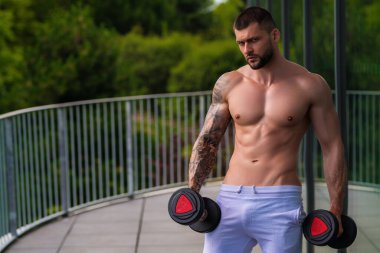 Muscular men lifting weights. Powerful male fit model doing workout in gym. Man lifting dumbells, strong athletic fit man doing exercises with dumbbells. Weightlifting workout. Fitness workout