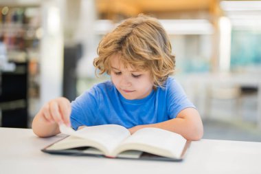Çocuk kitabı okuyor. Halk kütüphanesinde kitap okuyan çocuklar