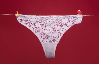 Tanga bikini iç çamaşırı, beyaz dantelli iç çamaşırı kırmızı arka planda izole edilmiş halat.
