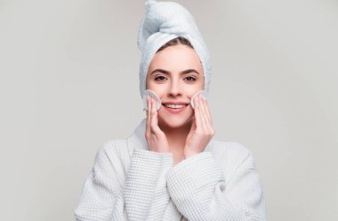 Genç bir kadın pamuk pedi kullanarak yüz derisini önemser.