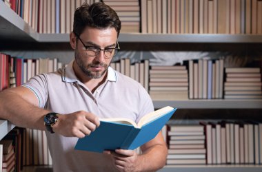 Kütüphanede kitap okuyan bir öğretmen. Öğretmenler günü, öğretmenler günü. Bilgi, eğitim. Kütüphanede ders veren bir öğretmen. Üniversite kütüphanesi. Öğretmenler edebiyat okuyor