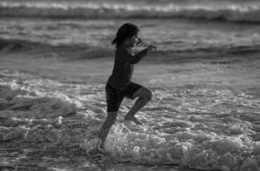 Heyecanlı çocuk yaz denizinde su sıçratarak oynuyor. Yaz tatili. Çocuk denizde dalgalarla oynuyor. Küçük çocuk denizde oynuyor ve su damlaları sıçrıyor. Çocuk denizde su sıçratmaca oynuyor. Yaz tatili