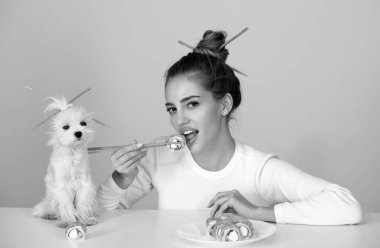 Japon suşi tarzı. Seksi kadın geleneksel Japon suşi ruloları yiyor. Kızın elinde yemek çubuklarıyla Japon suşi rulo Philadelphia 'sı var. Köpek evcil hayvanıyla reklam yapmak.