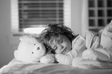 Sessiz bir uyku. Çocuk biraz kestir. Yatakta oyuncak ayıyla uyuyan bir çocuk. Yatak odasında rahat bir yatak. Yumuşak yastık, rahat, rahat yatak konsepti. Sağlıklı çocuklar uyuyor.