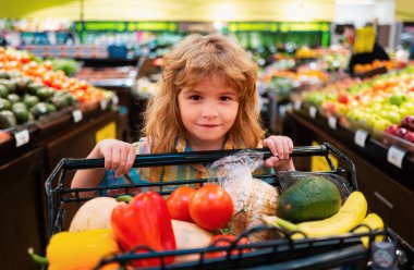 Sağlıklı çocuk yemekleri. Süpermarketteki çocuk sebze alır. Çocuklar süpermarketten alışveriş yapıyor.