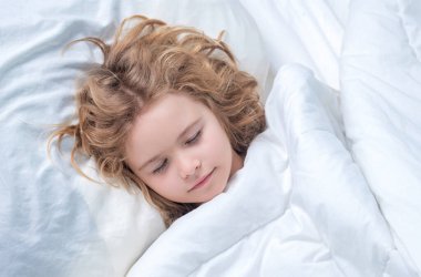 Uyku, uyku konsepti. Çocuk kestiriyor. Yatakta uyuyan çocuk, yatak odasında rahat bir yatak. Sağlıklı uyku konsepti. Yumuşak yastık, rahat, rahat yatak