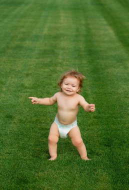 Şirin, komik, gülen bebek emeklemeyi öğreniyor çimlerde oynayıp, bahçede yazı izlerken eğleniyor. Bezi olan küçük eğlenceli bir çocuk.