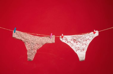 Külotlar kırmızı üzerine izole edilmiş. Kadın dantelli külot. İpe asılı erotik külotlar. Çamaşır ipinde kadın iç çamaşırı. Renkli erotik külot. Kadın iç çamaşırı