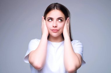 Öğrenci kız bir jestle sessizlik gösteriyor. Gri stüdyo arka planında izole edilmiş bir kadın. Parmağını dudaklarından çek ve sessiz ol. El hareketi sırrı. Sus, konuşma. Sessiz ol, sessiz ol, sır tut.