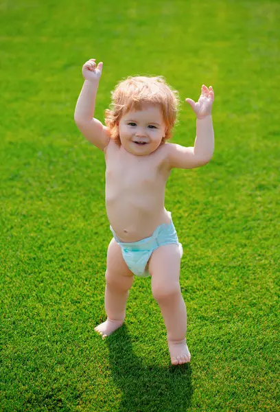 stock image Kids growing. Happy baby in grass on the fieald wearing a diaper at summer evening. Smiling child outdoors. Happiness and harmony in family life