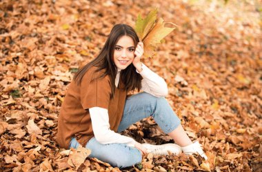 Sonbaharda güzel bir kız. Genç kadın sonbaharda sarı sonbahar yaprakları topluyor. Güzel kadın, sonbahar sarısı yaprağını tutar ve yüzüne düşer. Sonbahar döneminde şehvetli bir kadının portresi.