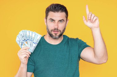 Adam sarı stüdyonun arka planına para koydu. Dolar banknotları olan zengin adamın portresi. Dolar banknotları olan başarılı bir adam. Zengin milyoner.