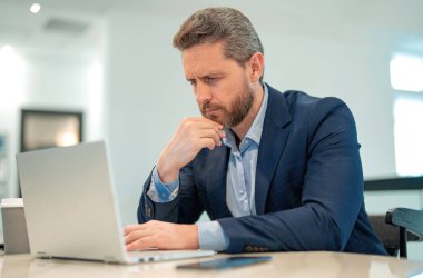 Ofiste çalışan ciddi bir iş adamı. Ofiste dizüstü bilgisayar kullanan sıradan takım elbiseli yakışıklı bir iş adamı. Resmi takım elbiseli bir ofis çalışanı. Ofis yöneticisi CEO iş adamı bilgisayar kullanıyor