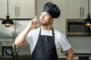 Yemek için fikir. Aşçı aşçı adam. Milenyum aşçı üniformalı erkek şef. Aşçı mutfakta yemek pişiriyor. Aşçı şapkalı ve önlüklü