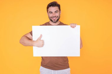 Boş afişi olan mutlu adam stüdyo arka planında izole edilmiş. Boş posteri olan çekici bir adamın portresi. Poster gösteren, tabela üzerinde parmak gösteren bir adam. Pano veya afiş konsepti